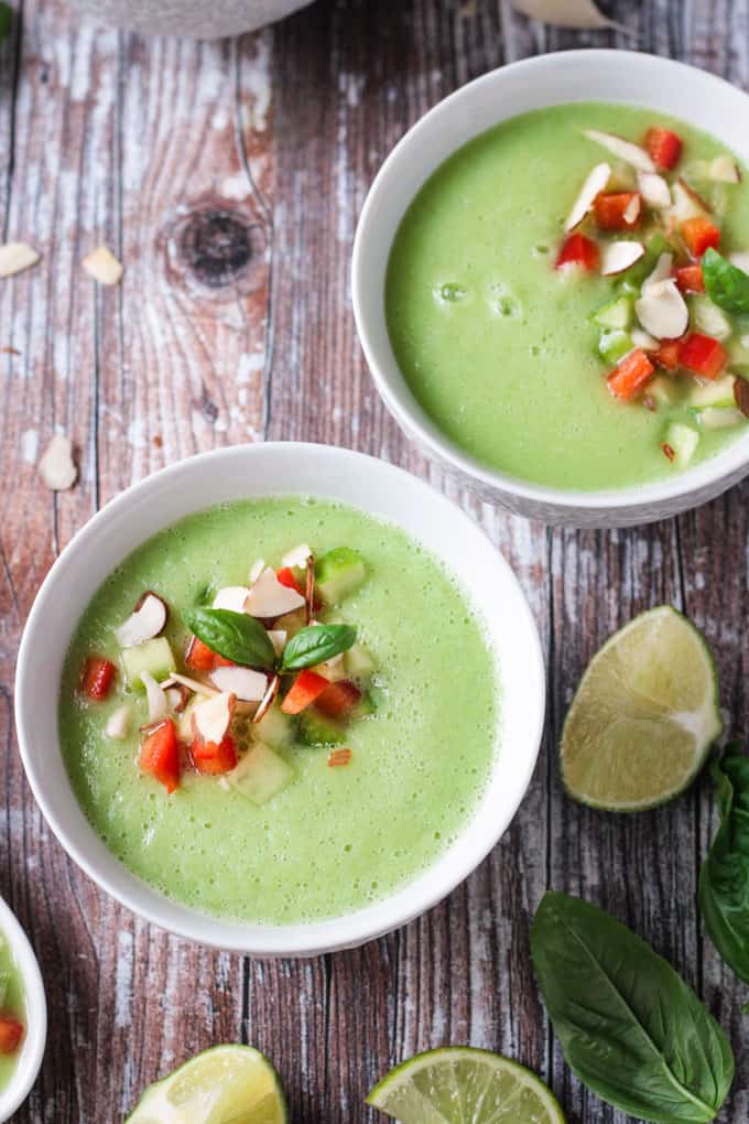 Two bowls of cold cucumber soup on a wooden table.