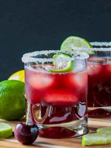 Three ice cubes floating in a glass of sparkling tart cherry lemonade.