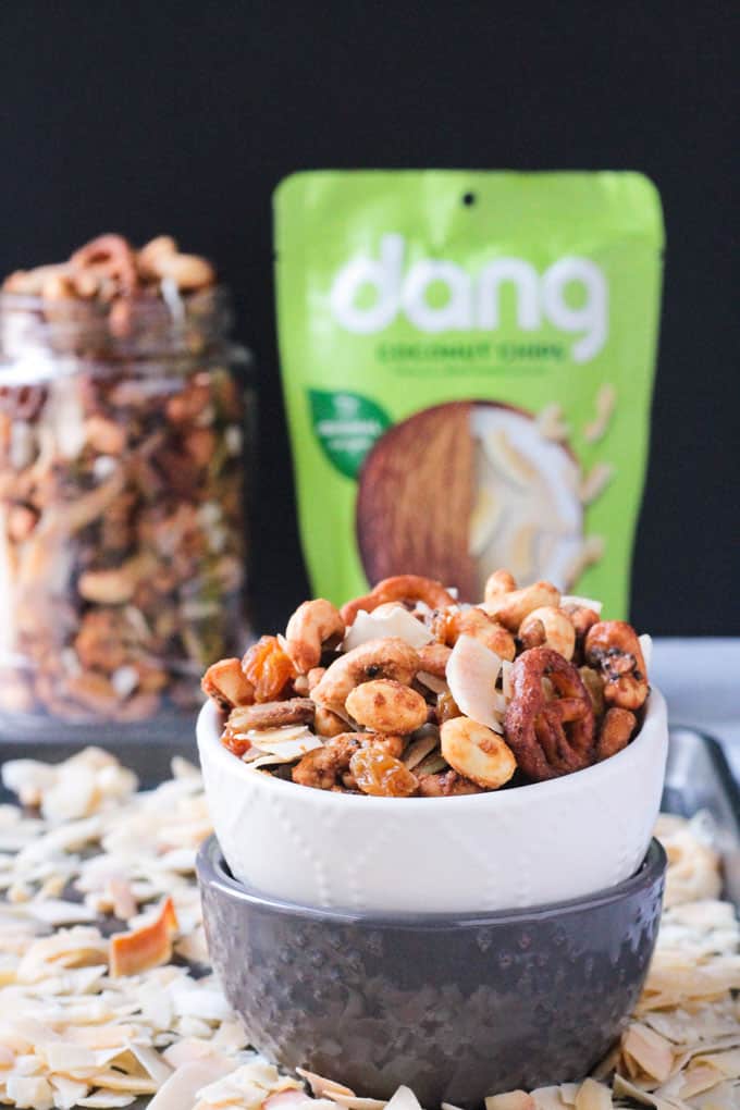 Homemade Trail Mix in a white bowl stacked on a gray bowl. Bag of Dang coconut flakes and a jar of trail mix behind.