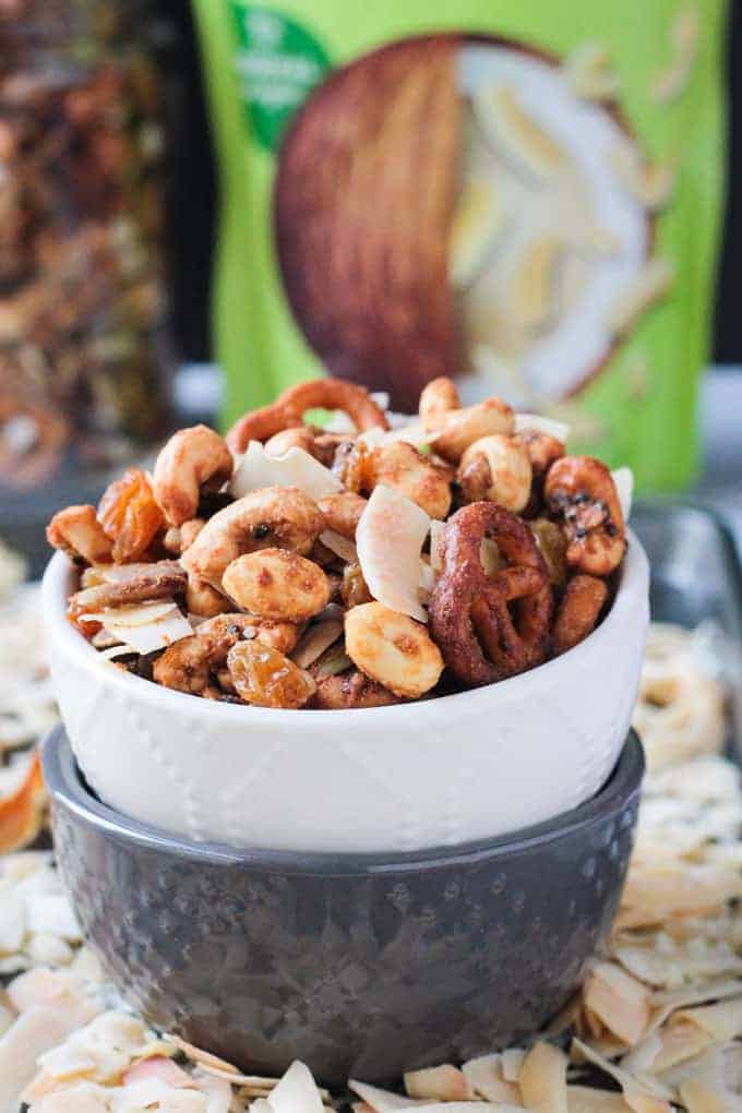 Close up front view of homemade trail mix in a white bowl stacked on top of a gray bowl.