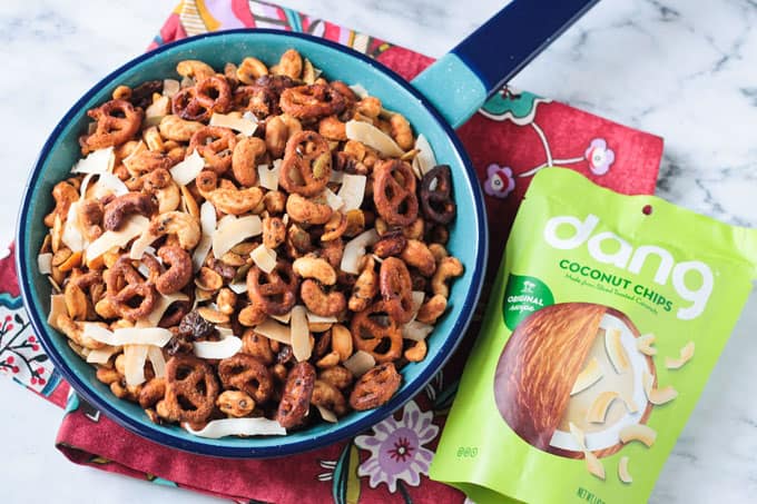 Thai flavored homemade trail mix in a blue skillet next to a green bag of Dang coconut flakes.