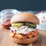 BBQ Chickpea Sandwich topped with creamy coleslaw and pickles on a whole wheat bun.