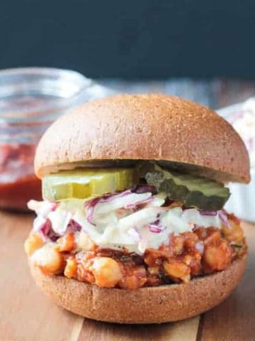 BBQ Chickpea Sandwich topped with creamy coleslaw and pickles on a whole wheat bun.