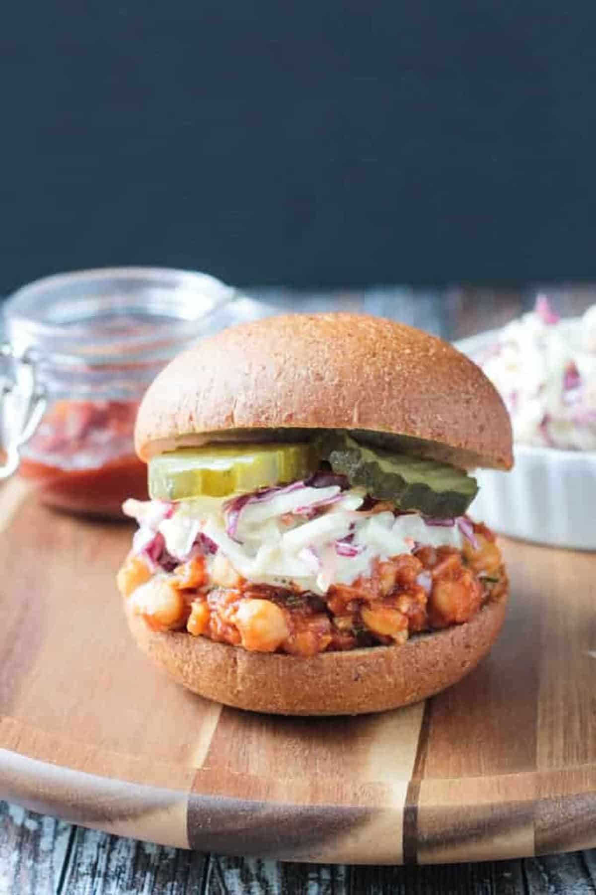 BBQ Chickpeas Sandwich topped with creamy coleslaw and pickles on a whole wheat bun.