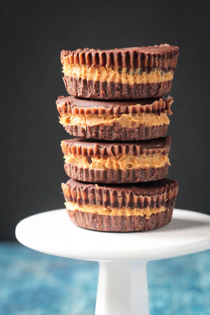 Close up front view of a stack of 4 dark chocolate vegan peanut butter cups.