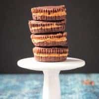 Stack of 4 dark chocolate peanut butter cups on a small white cupcake stand.