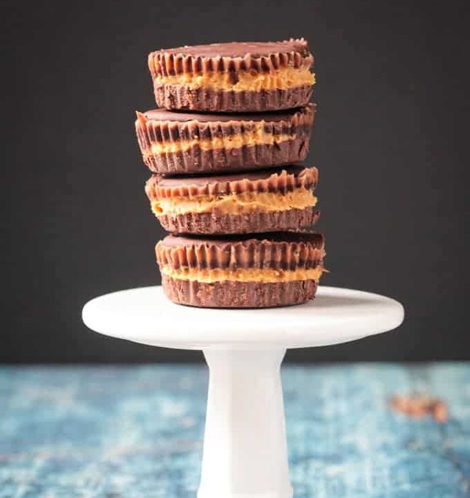 Stack of 4 dark chocolate peanut butter cups on a small white cupcake stand.