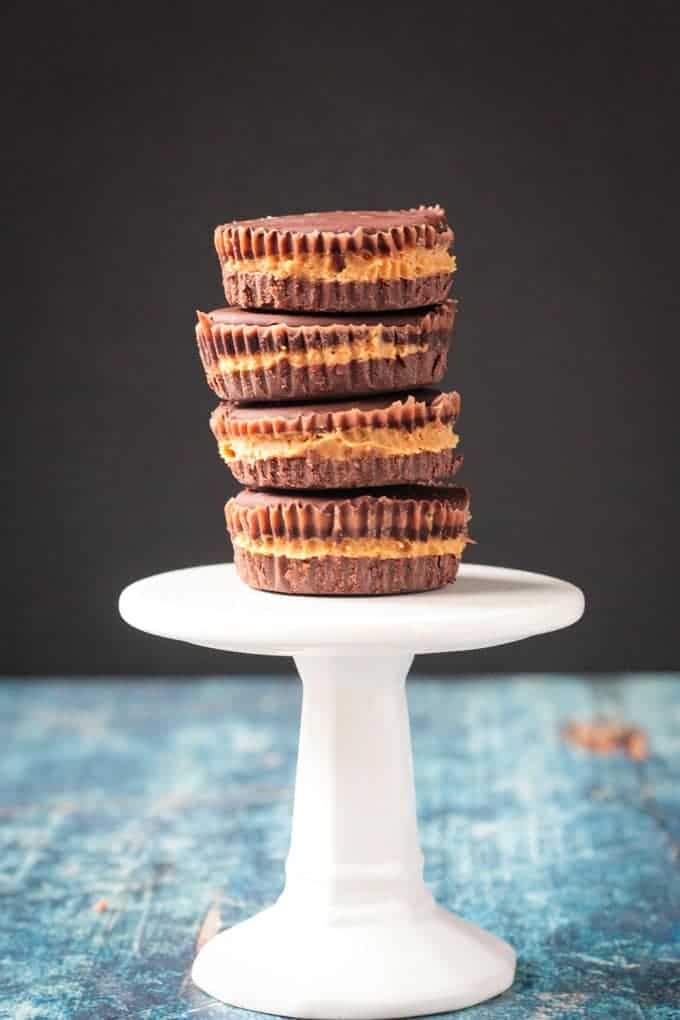 Stack of 4 dark chocolate vegan peanut butter cups on a small white cupcake stand.