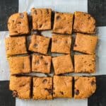 Dessert bars cut into 16 squares and haphazardly placed on sheet of parchment paper.