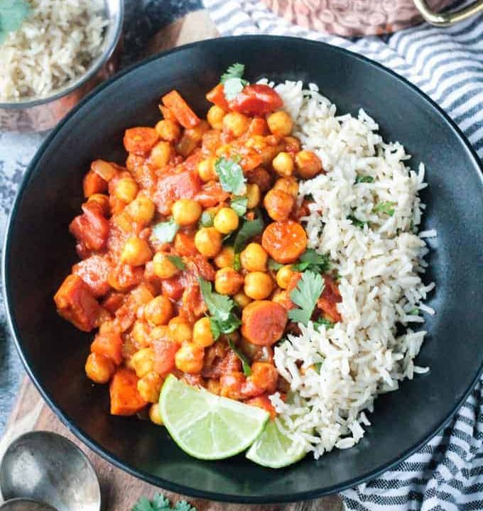 Overhead view of a black bowl of spiced chickpea stew and brown rice.