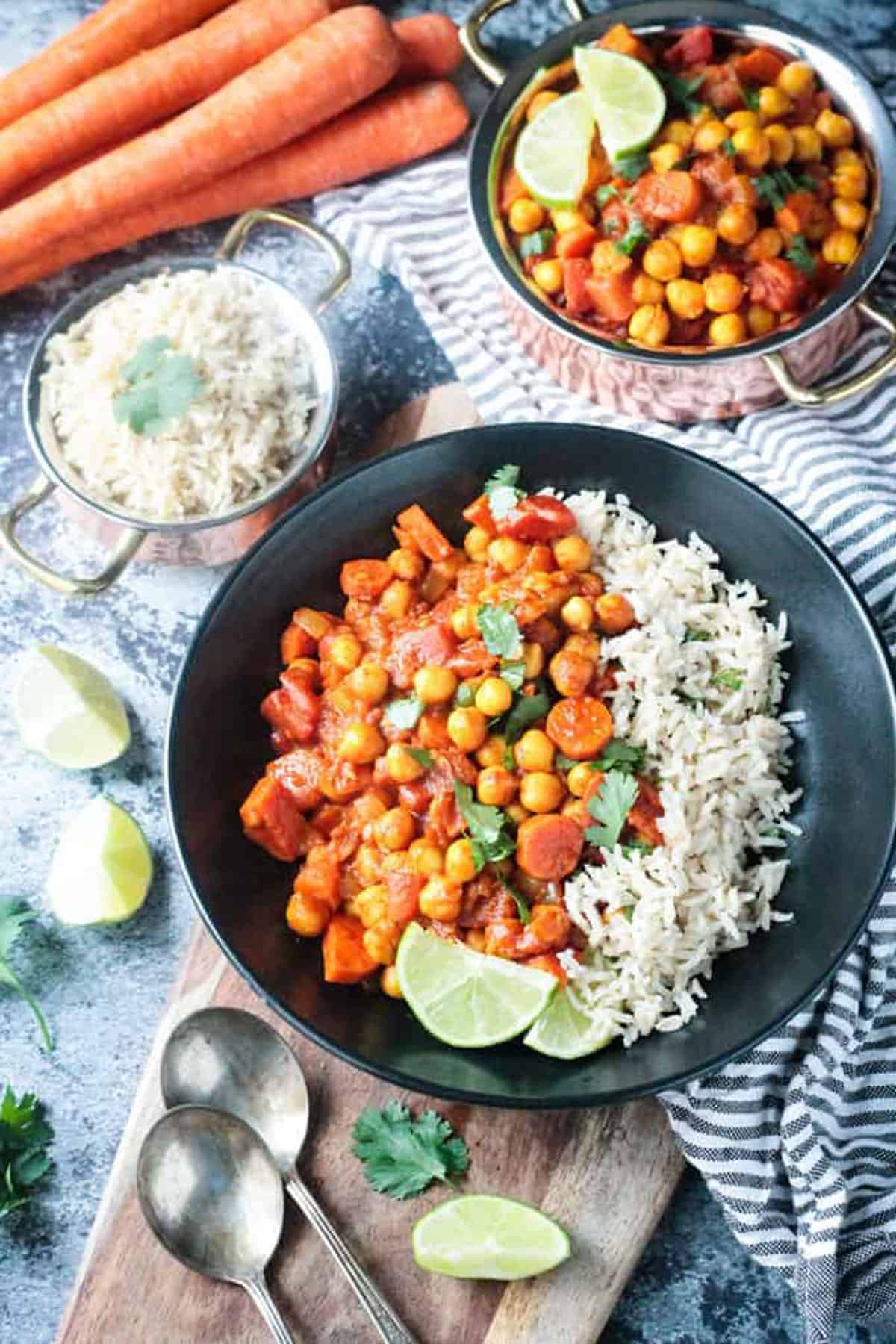 Chunky chickpea vegetable stew next to white rice in a black bowl.