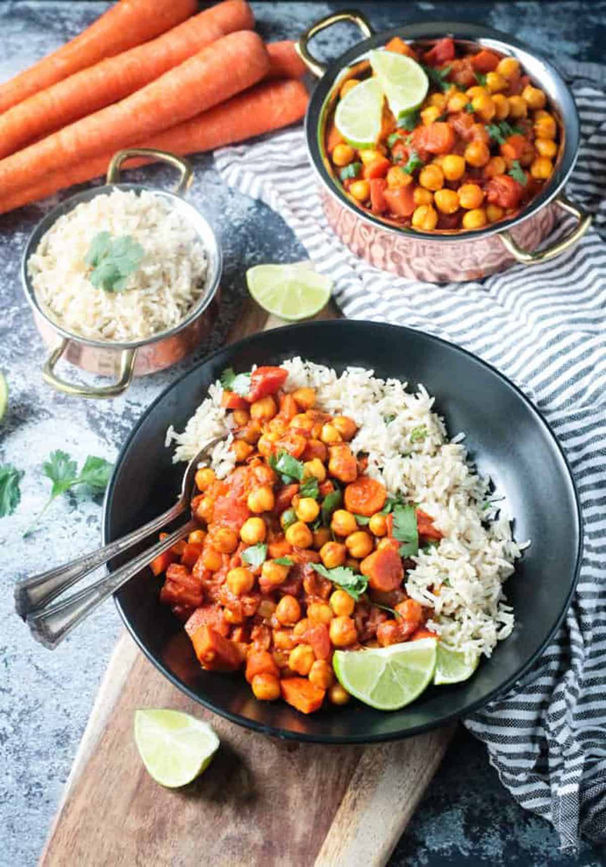 Two metal spoons in a bowl of the finished dish with rice.