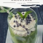 Green smoothie topped with whipped cream, chocolate chips, and a sprig of mint.