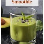 Green smoothie in a glass topped with a sprig of mint.