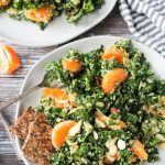 Kale and quinoa salad with orange segments and slivered almonds. Two seed and grain crackers on the side.