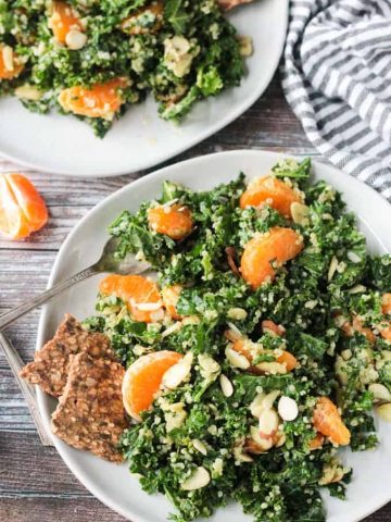 Kale and quinoa salad with orange segments and slivered almonds. Two seed and grain crackers on the side.