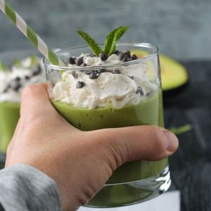 Hand holding a mint matcha smoothie in a glass.