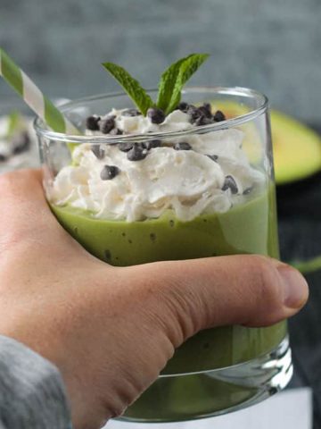 Hand holding a mint matcha smoothie in a glass.