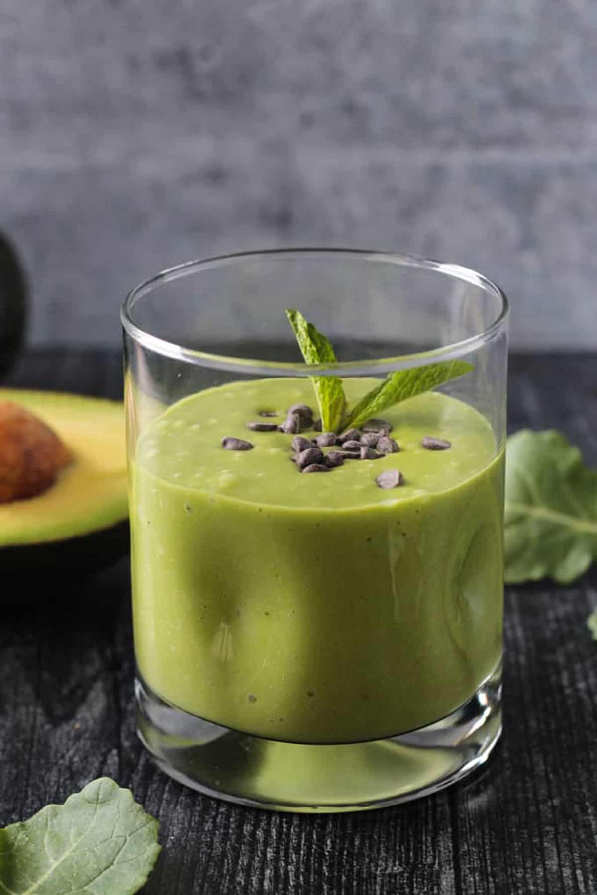 Green smoothie in a glass topped with a sprig of mint.