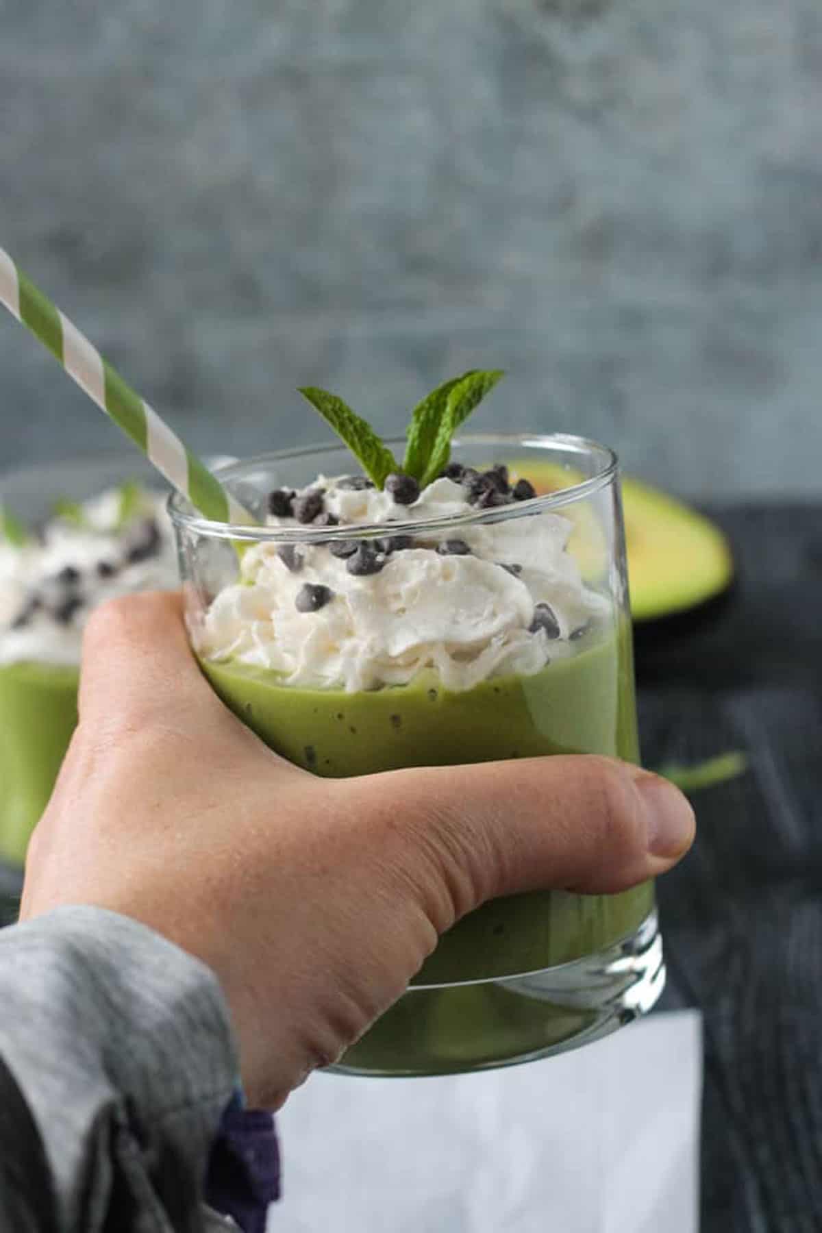 Hand holding a mint matcha smoothie in a glass.