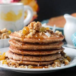 Close up of maple syrup drizzling down the side of a stack of carrot cake pancakes.