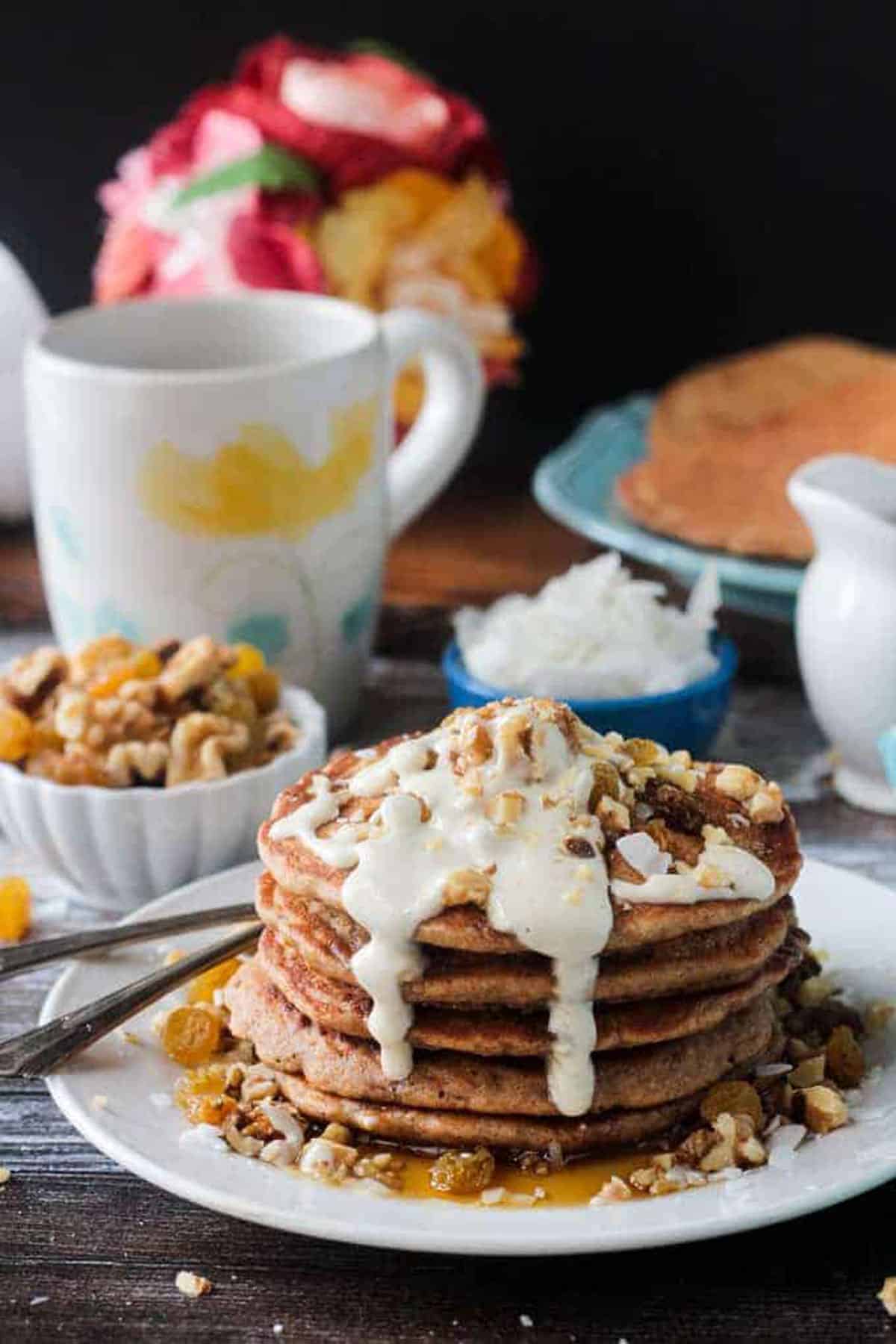 Chopped walnuts on top of white icing that is dripping down the side of a pancake stack.