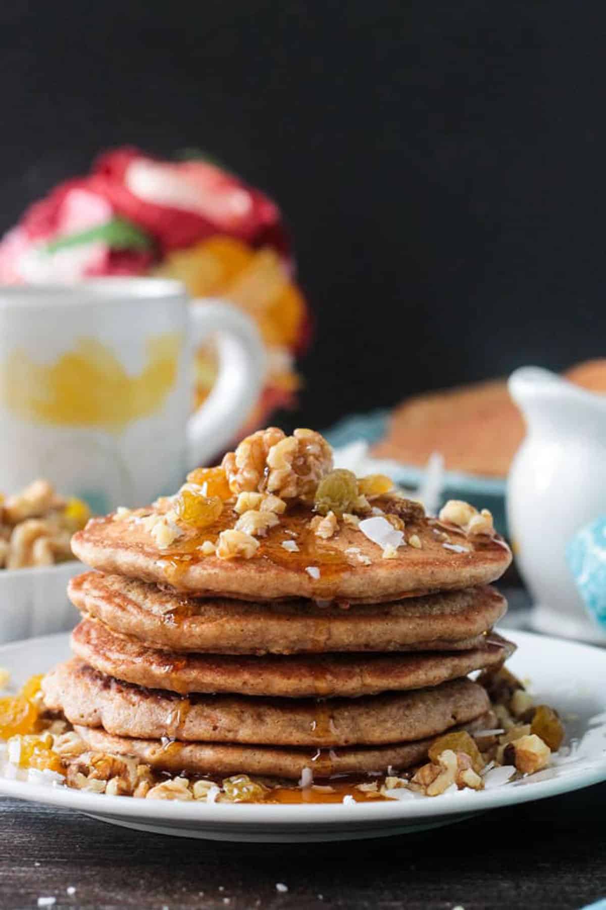 Close up of maple syrup drizzling down the side of a stack of carrot cake pancakes.