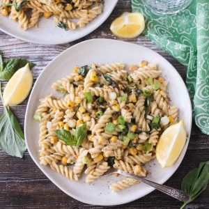 Plate of creamy sweet corn pasta topped with basil leaves.