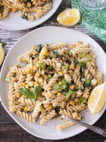 Plate of creamy sweet corn pasta topped with basil leaves.