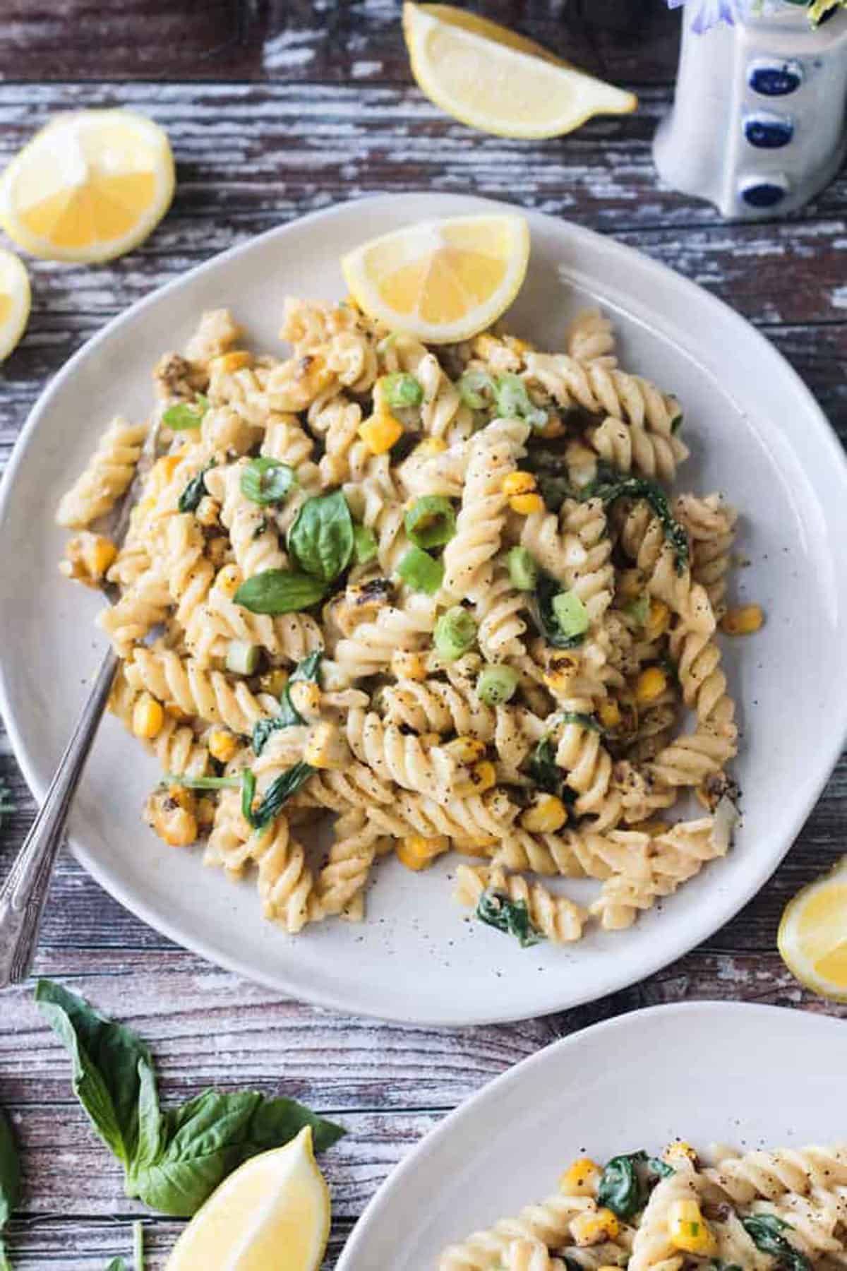 Plate of creamy sweet corn pasta topped with basil leaves.
