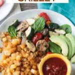 Breakfast plate with hash browns, sautéed veggies, and avocado.