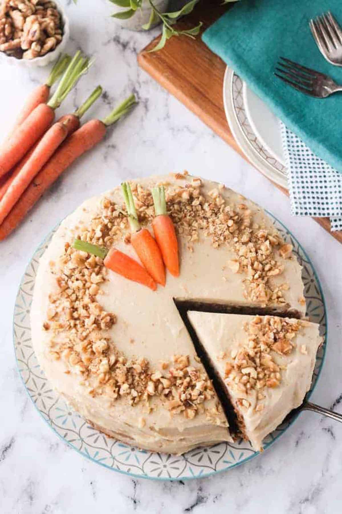 Overhead view of a carrot cake with a slice being taken out with a cake spatula.