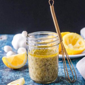 Lemon vinaigrette in a small glass jar next to a whisk.