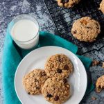 Three oatmeal breakfast cookies on a white plate next to a glass of milk.