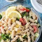 Bowl of vegan pasta salad with rotini noodles, broccoli, cucumber, artichokes, and tomatoes.