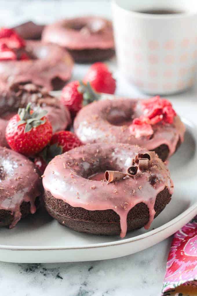 close up of a chocolate donut with drippy strawberry glaze