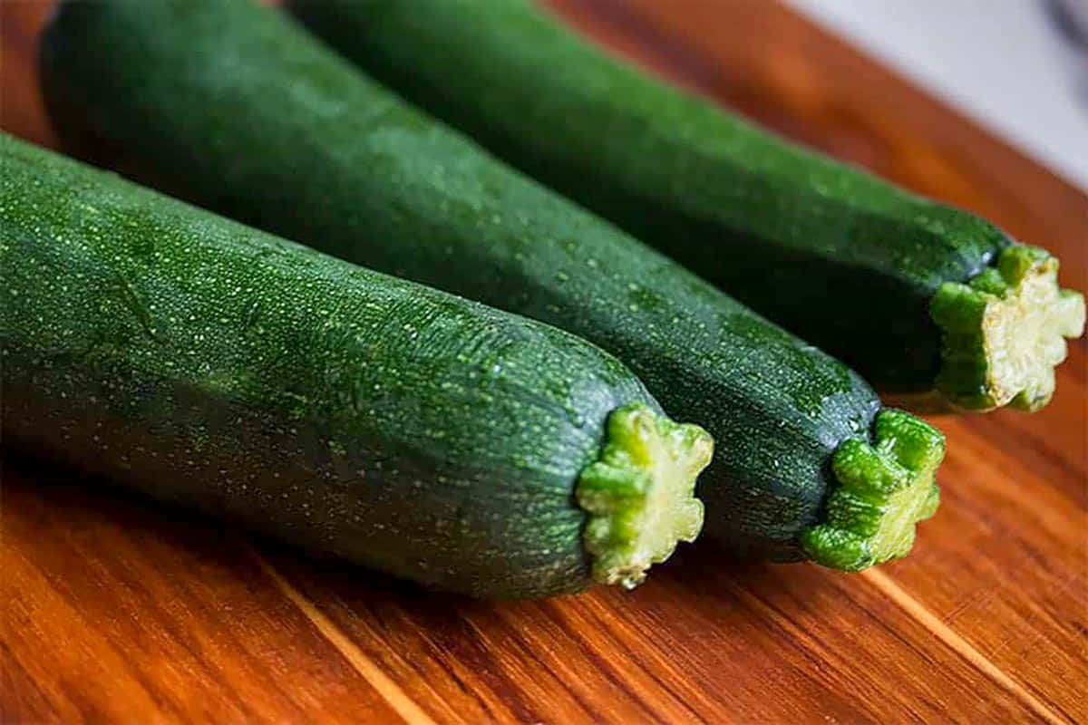 Three zucchini squash on a cutting board.