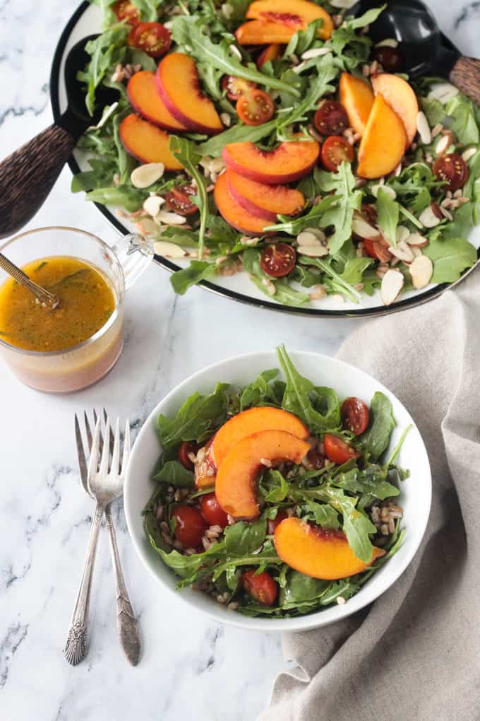 Small bowl of salad in front of a large platter of salad