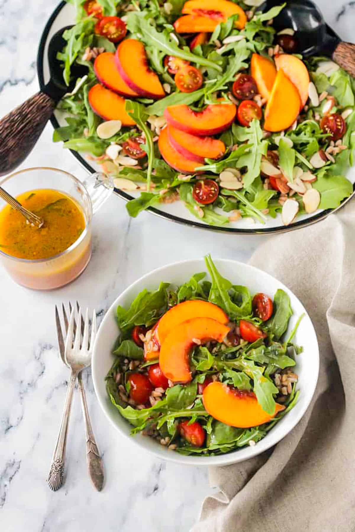 Small bowl of salad in front of a large platter of salad.
