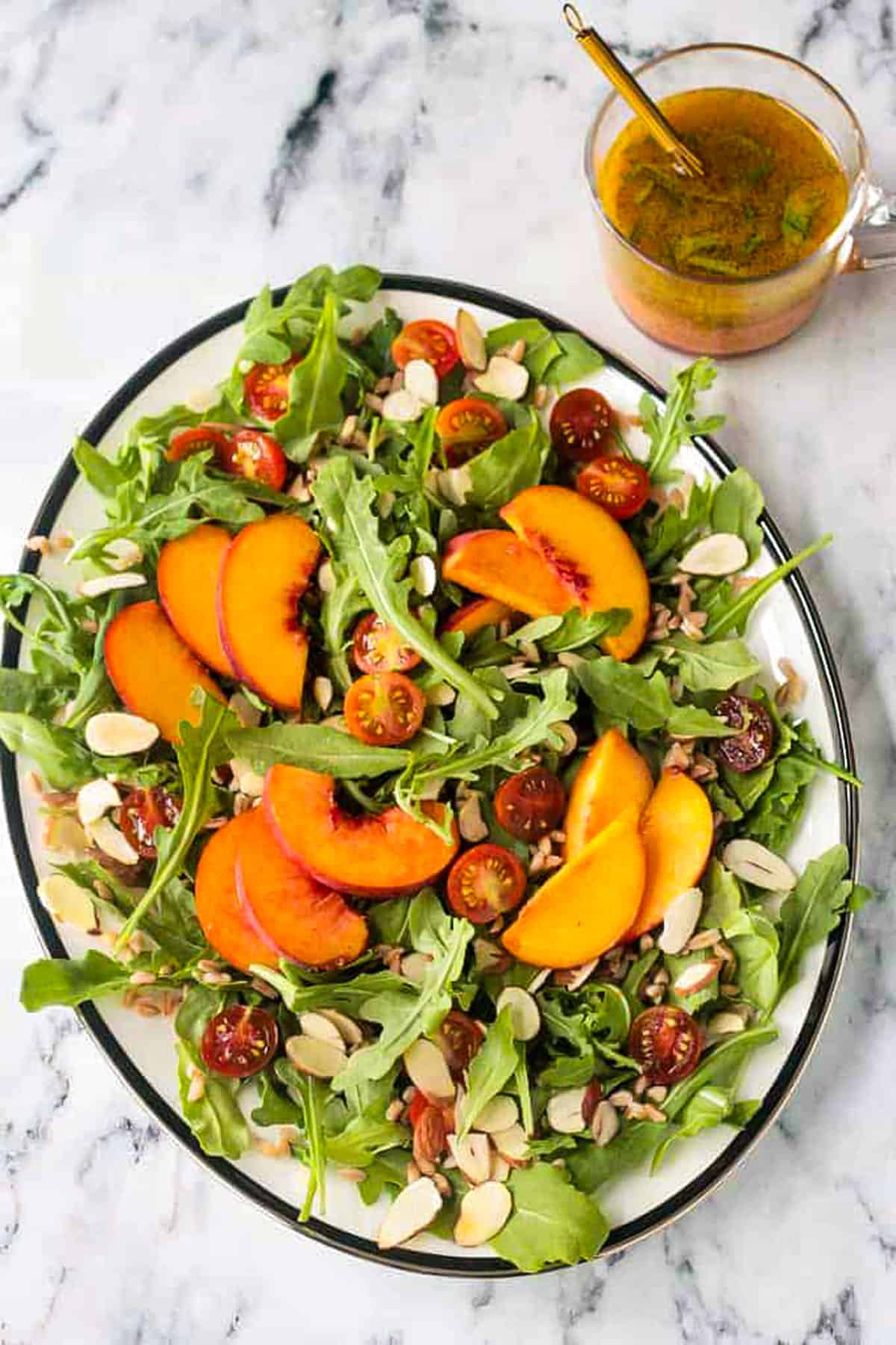 Arugula salad with sliced peaches, grape tomatoes, slivered almonds, and farro.