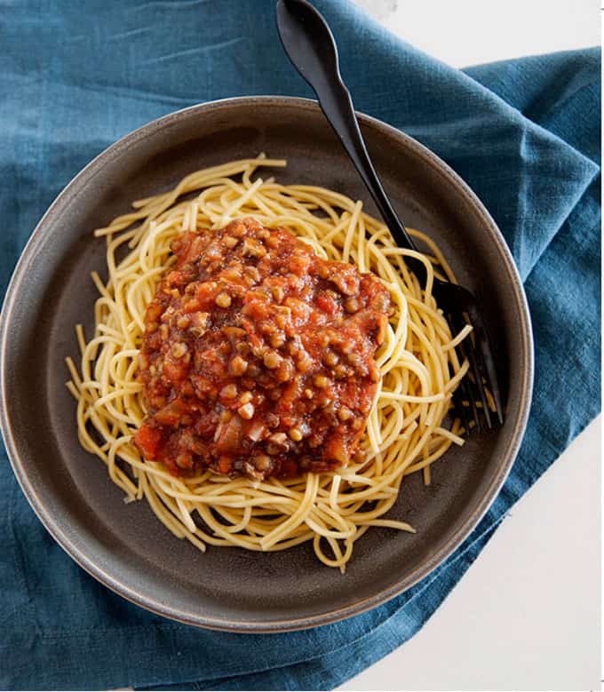 Spaghetti with lentil sauce in a dark gray bowl