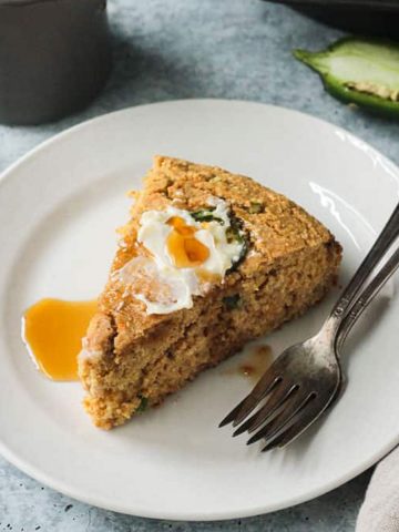 One slice of vegan jalapeño cornbread topped with butter and maple syrup.