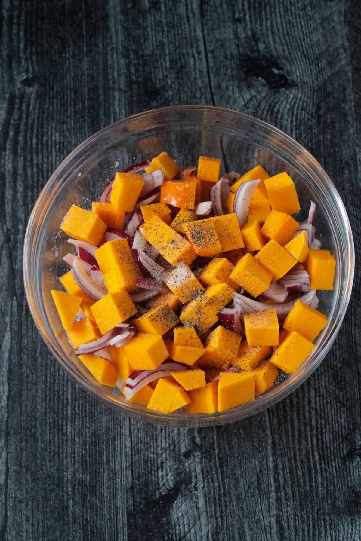 Chopped raw vegetables in a mixing bowl with spices.