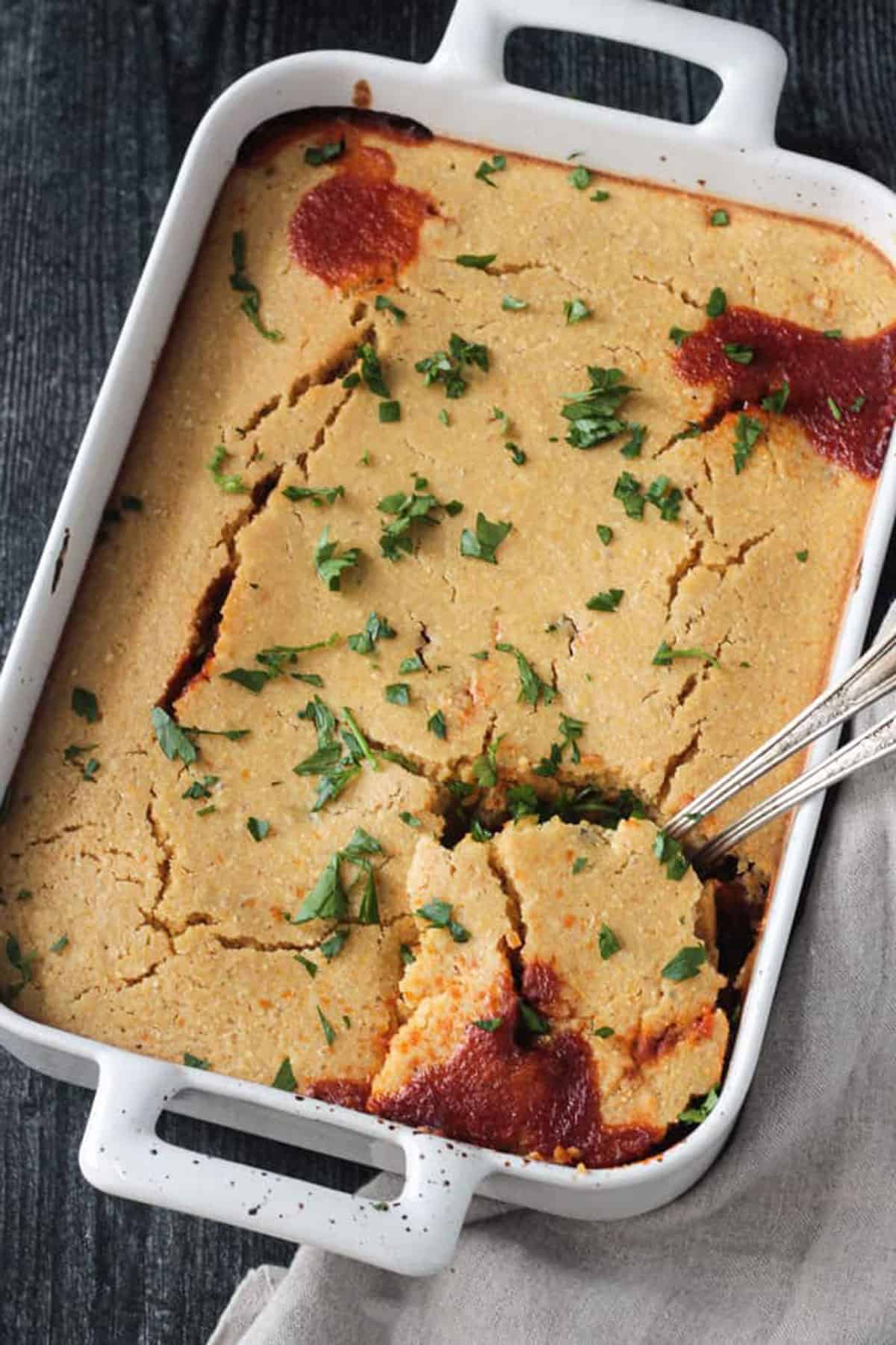 Two spoons scooping out a portion of this recipe from a baking dish.