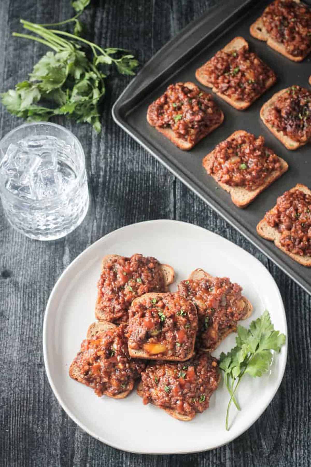 Plate of rye toast appetizers with a pan of more behind.