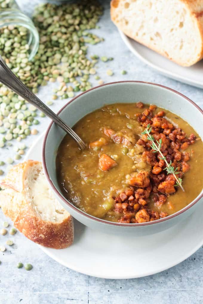 Slice of buttered bread lies next to a bowl of soup