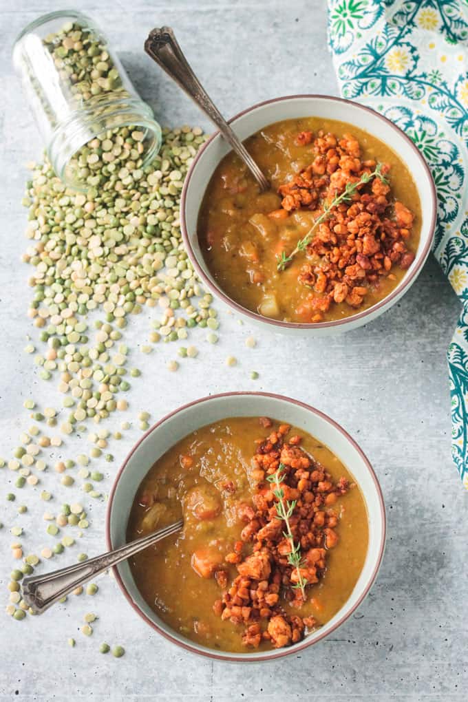 Overhead view of two bowls of soup with spoons in them.