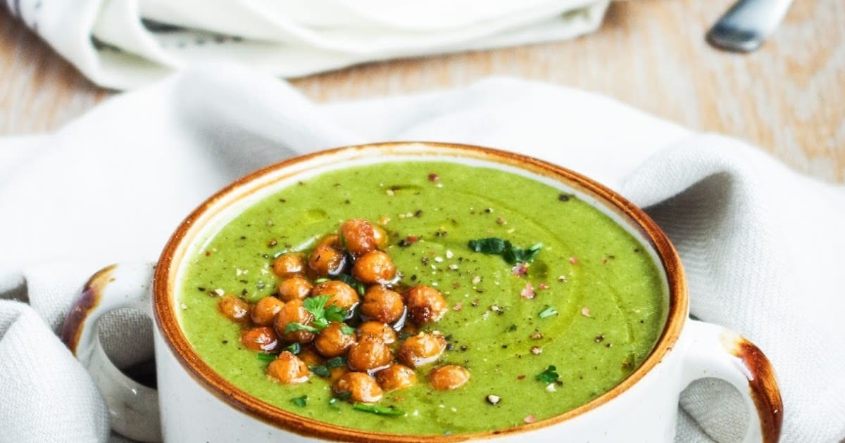 bowl of green soup with a pile of chickpeas on one side