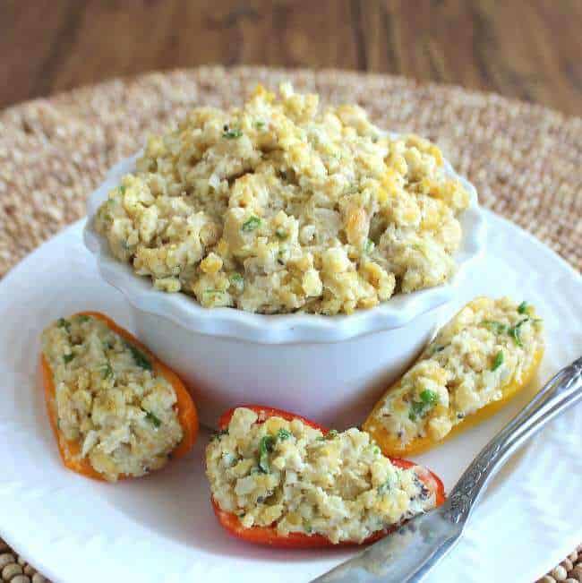 mini peppers stuffed with mashed chickpea mixture on a plate with a bowl of more filling