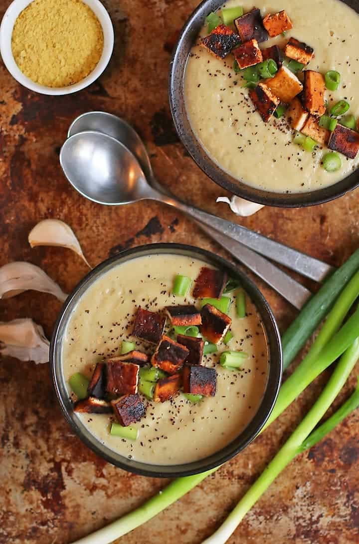 two bowls of creamy soup next to two spoons